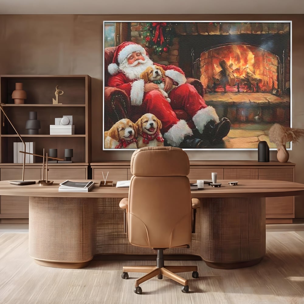 Tablou canvas cu mos craciun dormind cu catei langa semineu, in rama de aluminiu argintiu, pe perete intr-un birou